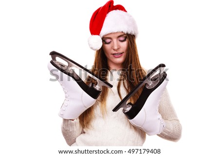 Winter skate sport people concept. Girl with santa claus cap. Young woman has white outfit and long beautiful hair, female holding two ice skates.