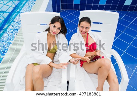 Young girls friends messaging with friend on her smartphone. Relaxation spa and technology social networks concept.