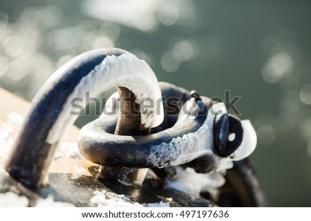Grey metal hook with snow and blurred sea background 