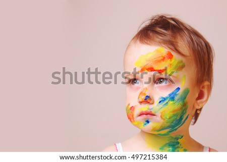 beautiful baby girl painted colors looks into the distance (make-up, humorous picture)