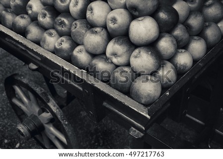 Organic apples stacked in wooden cart for sale in farmers market . Black and white photo.