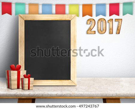 Happy new year on blackboard with gift and colorful flag banner on marble table at white wall,Leave space for display or montage of your design