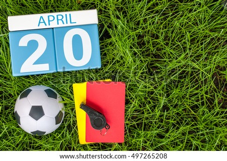 April 20th. Day 20 of month, calendar on football green grass background with soccer outfit. Spring time, empty space for text