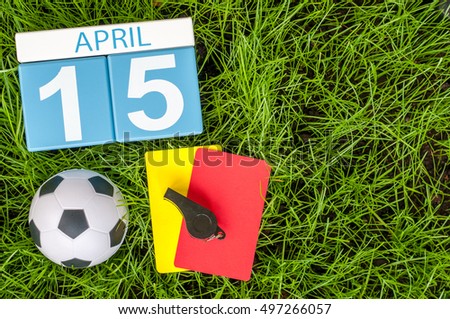 April 15th. Day 15 of month, calendar on football green grass background with soccer outfit. Spring time, empty space for text