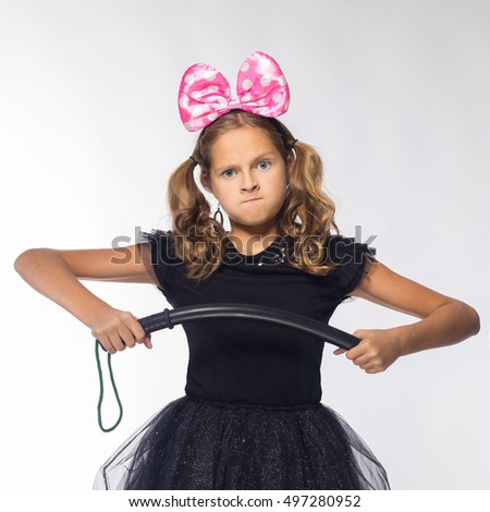 emotional girl actress cheerful blonde in a black dress with a pink bow and a rubber baton on a white background
