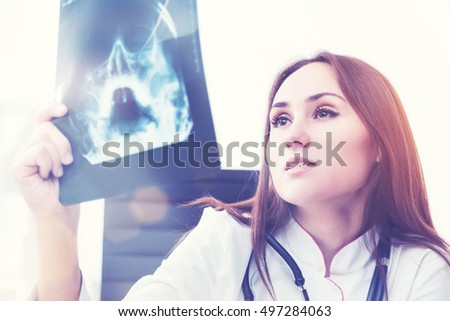 Female doctor looking at X-rays. Light background. Concept of work. Toned image