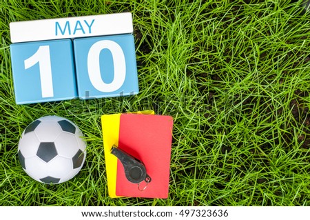 May 10th. Day 10 of month, calendar on football green grass background with soccer accessories. Spring time, empty space for text