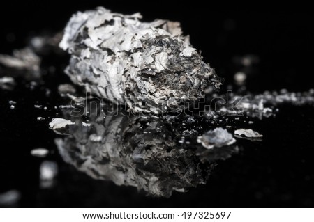 Macro shot of cigarette ashes on glass surface, isolated on black backround. Copy space for your text