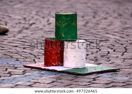 Bowling game with three tin cans with the colors of the Italian flag. Ancient street game in Verona, Veneto Italy, Europe