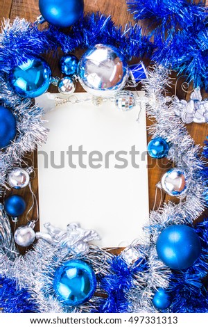 New Year, blue and silver Christmas decorations, around a white sheet of paper. On a wooden background.