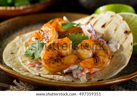 Delicious spicy shrimp taco with creamy cilantro slaw and lime. Royalty-Free Stock Photo #497359351