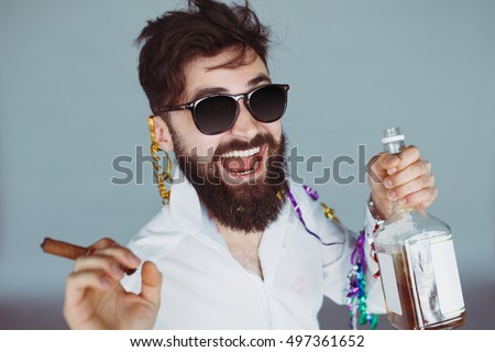 Bearded man with sunglasses holding a bottle of alcohol and cigar at celebration. Ecstatic portrait of drunk man having fun at wild party. Toned colors image
