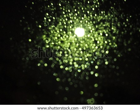 The green bokeh background in the dark night and raining today