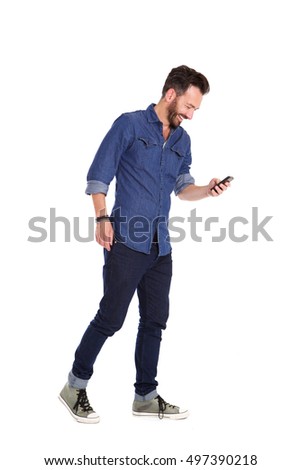 Full body portrait of smiling mature man walking and using mobile phone over white background