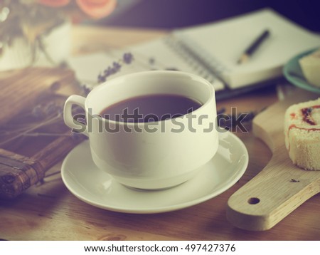 Coffee mug with cupcake, notebook and pencil on rustic table from above, cozy and sweet breakfast, good morning or have a nice day concept