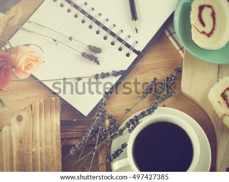 Coffee mug with cupcake, notebook and pencil on rustic table from above, cozy and sweet breakfast, good morning or have a nice day concept