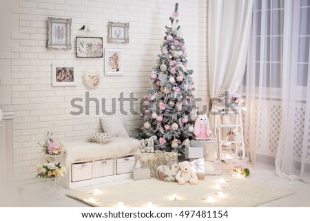 Christmas tree in pink shabby chic style at the white brick wall background. Vintage clock and retro pictures on the wall. New year background.