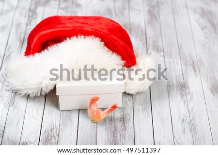 Santa Claus hat over gift box on wooden background. Winter holidays concept. New Year of a rooster.