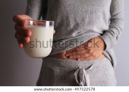 Woman with stomach pain holding a glass of milk. Dairy Intolerant person. Lactose intolerance, health care concept. Royalty-Free Stock Photo #497522578