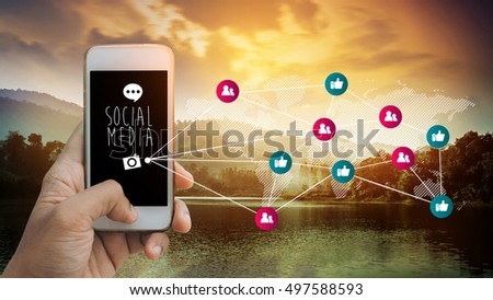 Man's hands holding smart phone emitting holographic image of social media related icons on the mountain lake