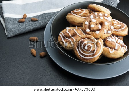 Twisted buns with cinnamon and icing sugar on a black background