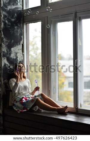 woman making bubbles on windowsill in loft room apartment