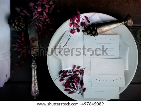 white plate with old silver knife and pieces of paper on a wooden background. space for text. top view