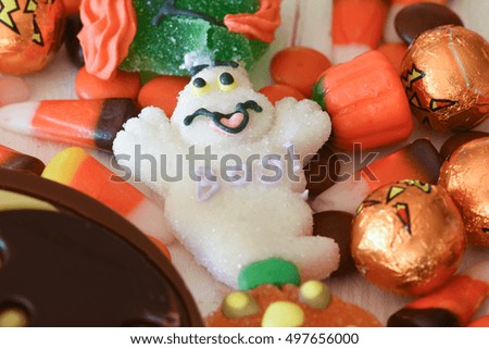 A close up of a candy ghost, chocolates and other Halloween candies on a white wooden surface