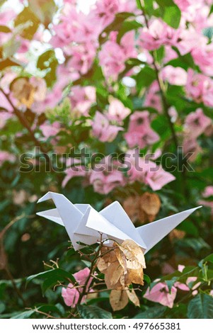 paper white crane sit on dead flower blurred background