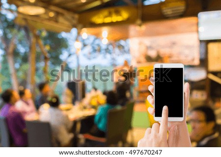 woman use mobile phone and blurred image of people in the restaurant