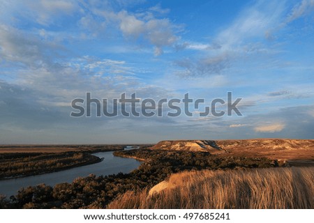Golden sunset on the river. Autumn landscape. Beautiful clouds and hills.