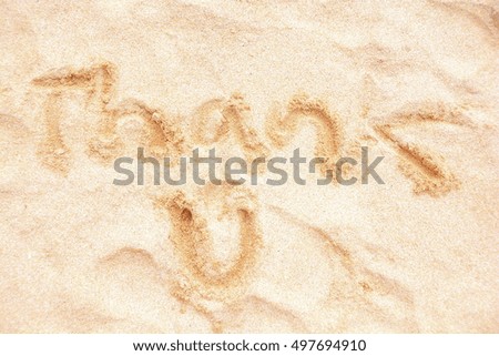 thank you written with finger on sandy beach