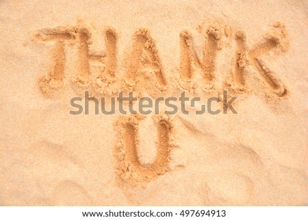 thank you written with finger on sandy beach