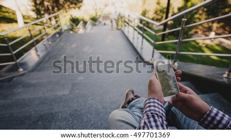 Close up a man taking photos of nice view with his smart phone while sitting on stairs
