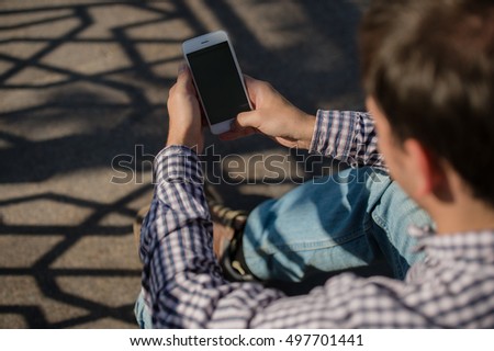 Man uses his Mobile smart Phone outdoor while sitting on a stairs, close up