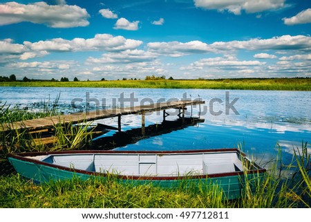 Wooden river pier with a fishing boat on the shore of the river. Landscape. Nobody