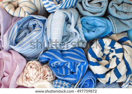 Cotton pastel fabrics for sewing shirts. Sewing accessories. Scissors, thread and buttons on a brown background.