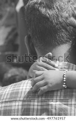 Father's back with daughter's arms around his neck. Vintage effect, black and white photography