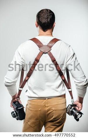 
Handsome photographer with handmade camera support strap against gray background.