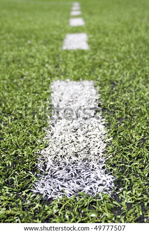 Green grass and sport lines painted at an outdoor playing field (artificial covering). Photographed with shallow DOF