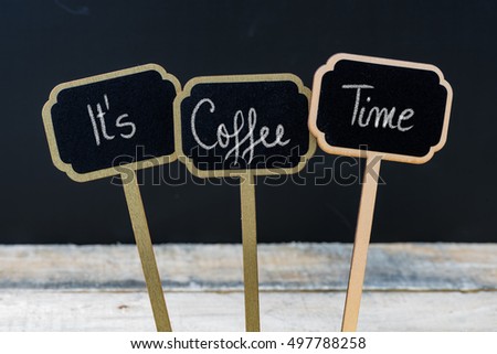Motivational message Its Coffee Time written with chalk on wooden mini blackboard labels, defocused chalkboard and wood table in background