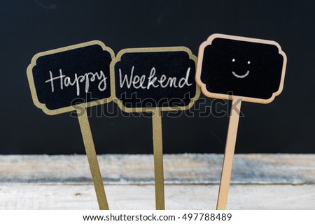 Motivational message Happy Weekend written with chalk on wooden mini blackboard labels, defocused chalkboard and wood table in background
