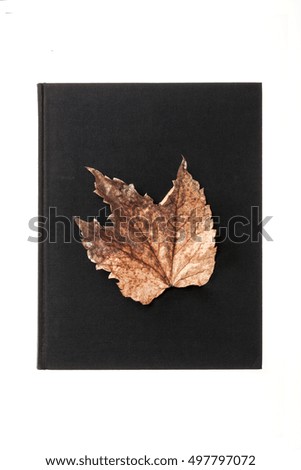 A black fabric covered book with dry leaf for autumn(fall) isolated white.
