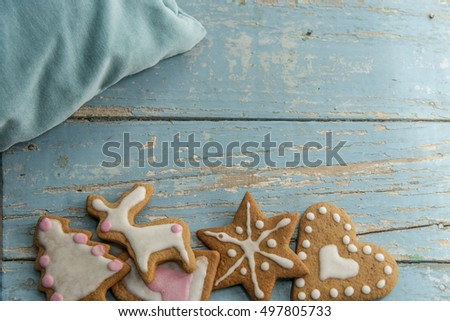 Christmas background. Handmade gingerbread cookies with white and pink icing on a blue table with a blue pillow.