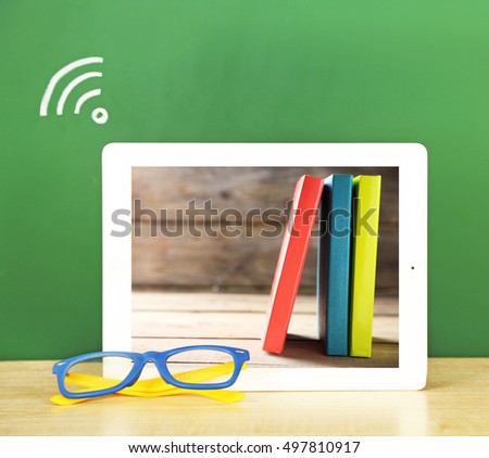 Tablet with stationery wallpaper on screen. WI-FI sign on chalkboard background. School teacher concept.