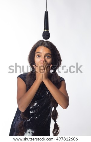 young brunette girl with long hair in black dress with microphone on a white background