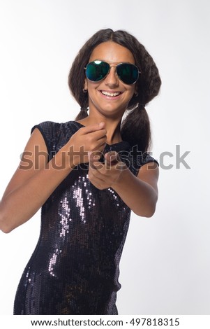 emotional young girl actress brunette wearing sunglasses in black dress on a white background