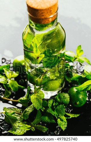 mojito bottle with lime and mint ice cube close-up on dark background.
