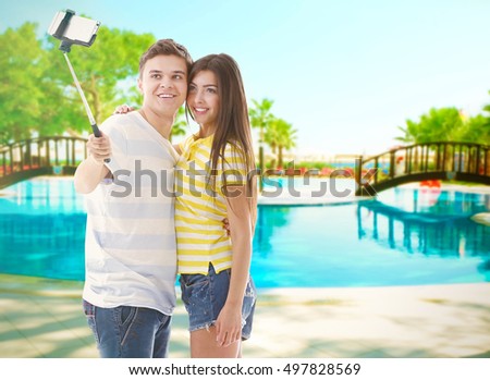 Young happy couple taking selfie on blurred swimmng pool background.