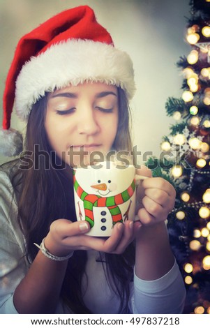 Young pretty woman under new year tree with christmas cup of chocolate